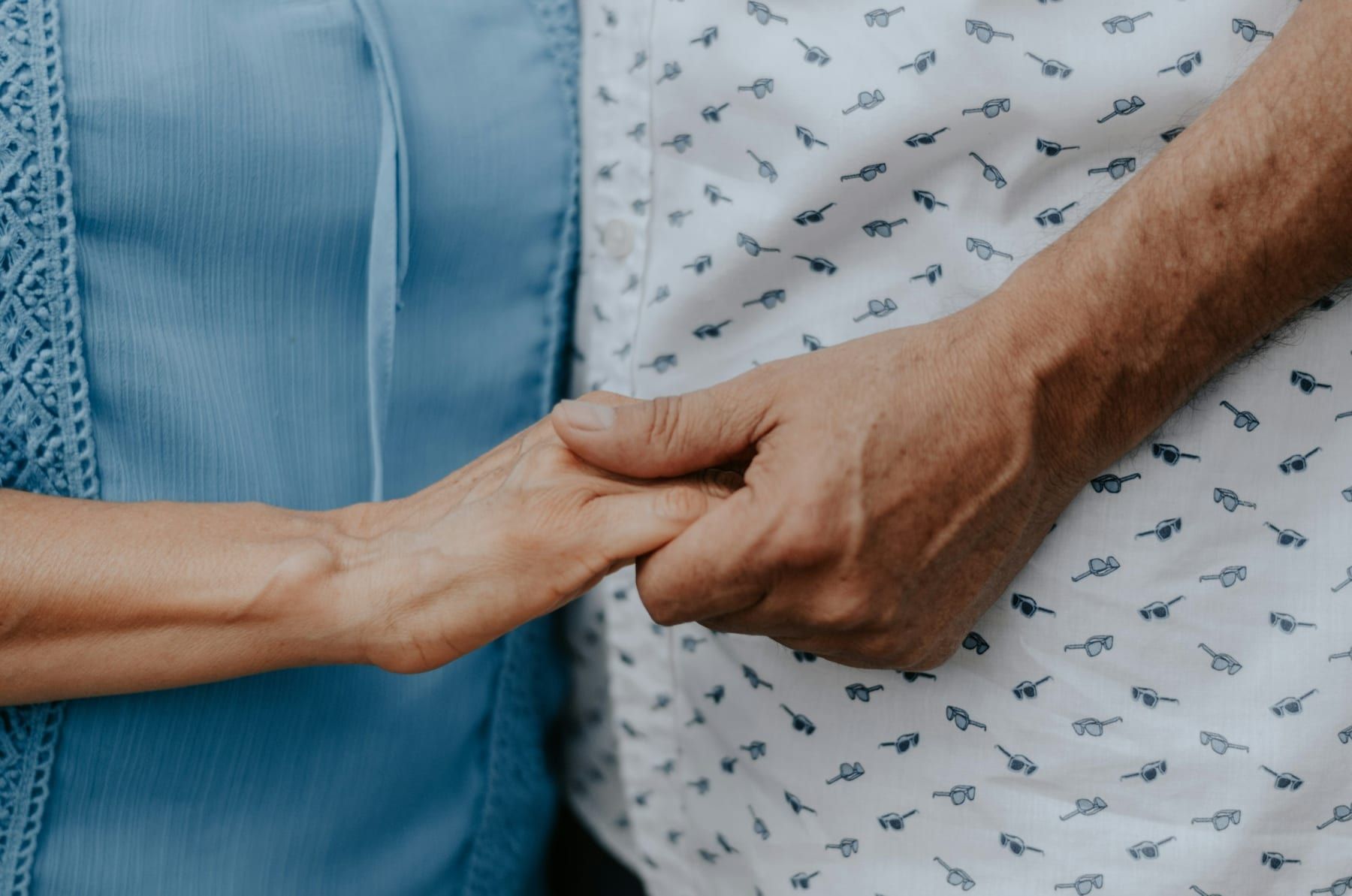 Close-up of two people holding hands in support