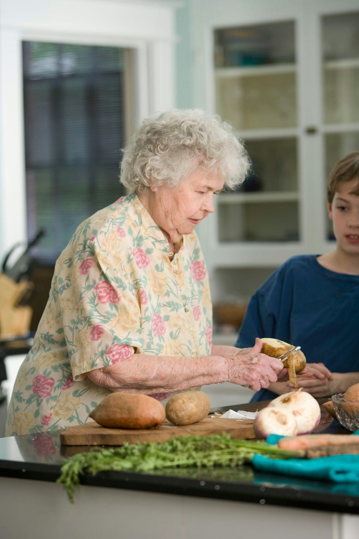 An older woman prepares fresh vegetables in her kitchen